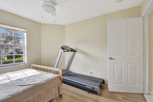 bedroom featuring lofted ceiling, ceiling fan, light hardwood / wood-style flooring, and a textured ceiling