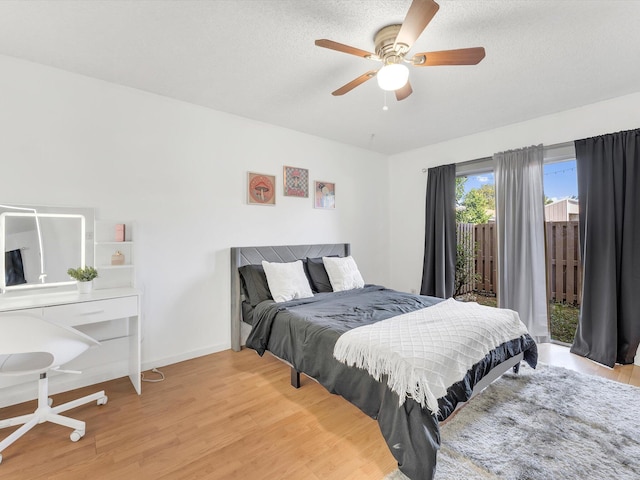 bedroom featuring ceiling fan, access to exterior, light wood-type flooring, and a textured ceiling