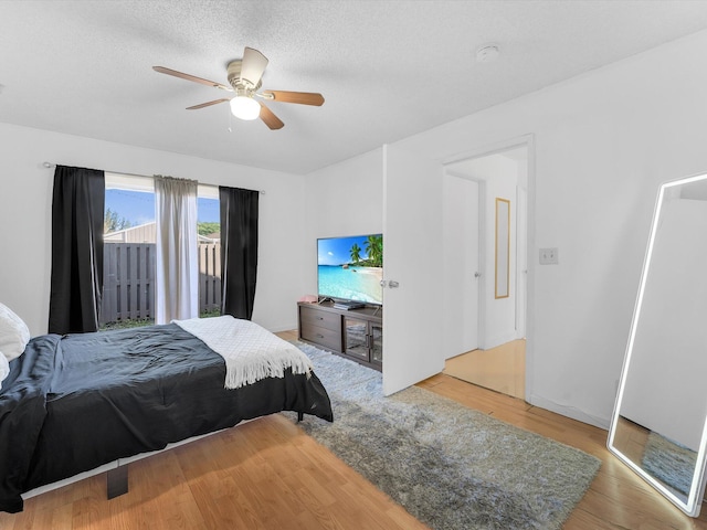 bedroom with access to exterior, ceiling fan, a textured ceiling, and hardwood / wood-style flooring