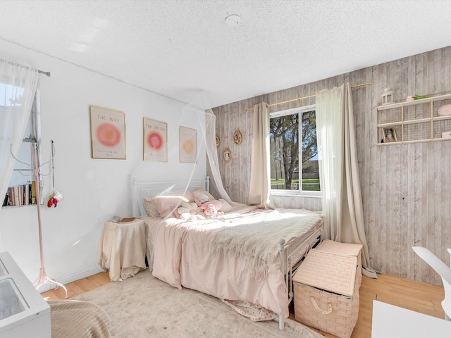 bedroom featuring wood-type flooring, a textured ceiling, and wood walls