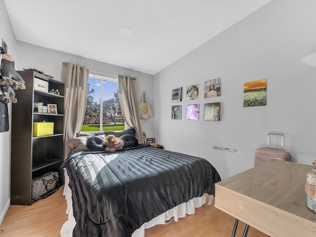 bedroom with vaulted ceiling and light hardwood / wood-style flooring