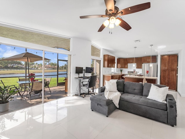 living room featuring ceiling fan, sink, a water view, and light tile patterned flooring