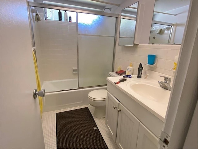 full bathroom with tasteful backsplash, shower / bath combination with glass door, vanity, tile patterned flooring, and toilet