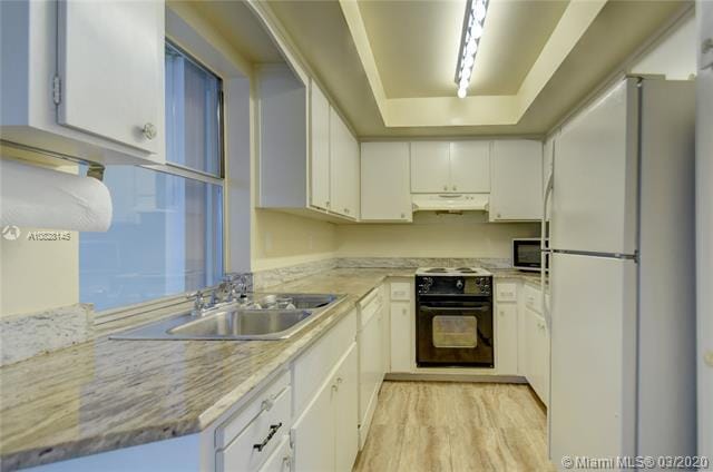 kitchen with white cabinetry, sink, white refrigerator, and black stove