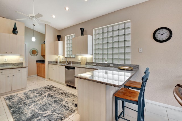 kitchen featuring kitchen peninsula, a breakfast bar, dark stone countertops, dishwasher, and lofted ceiling