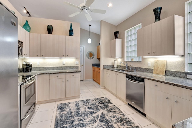 kitchen featuring lofted ceiling, dark stone counters, sink, appliances with stainless steel finishes, and decorative light fixtures