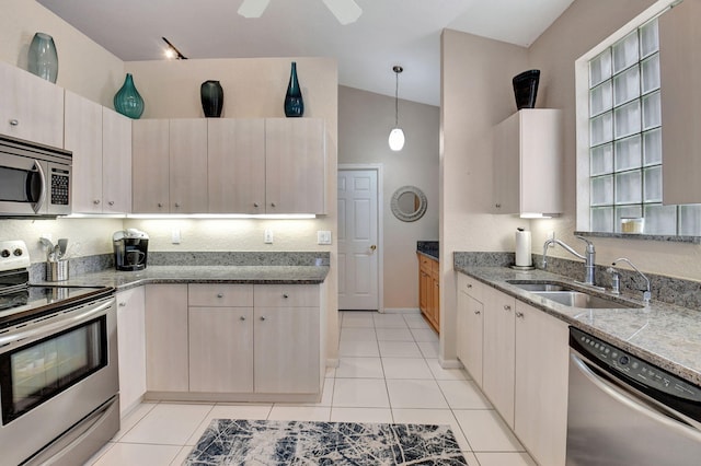 kitchen with appliances with stainless steel finishes, sink, pendant lighting, lofted ceiling, and light tile patterned flooring