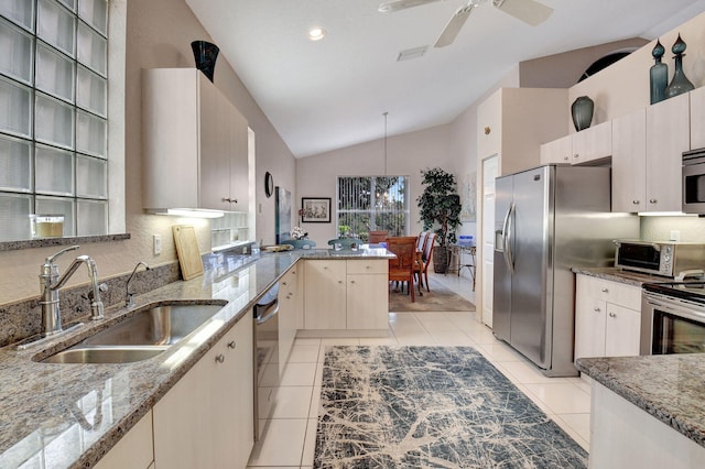 kitchen with appliances with stainless steel finishes, light stone counters, vaulted ceiling, sink, and hanging light fixtures