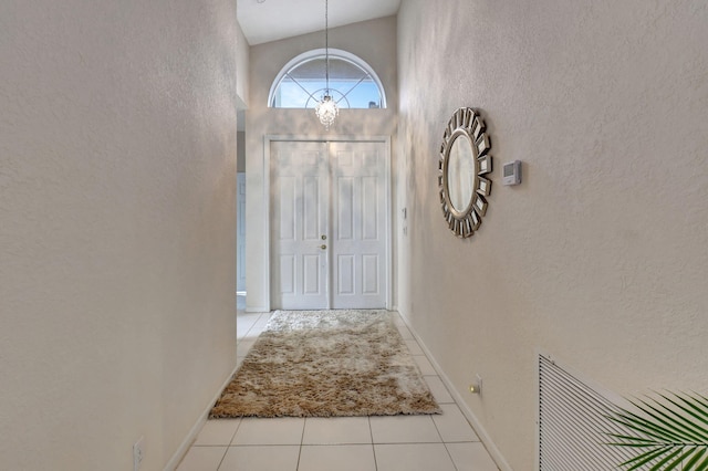 doorway to outside with light tile patterned floors and high vaulted ceiling