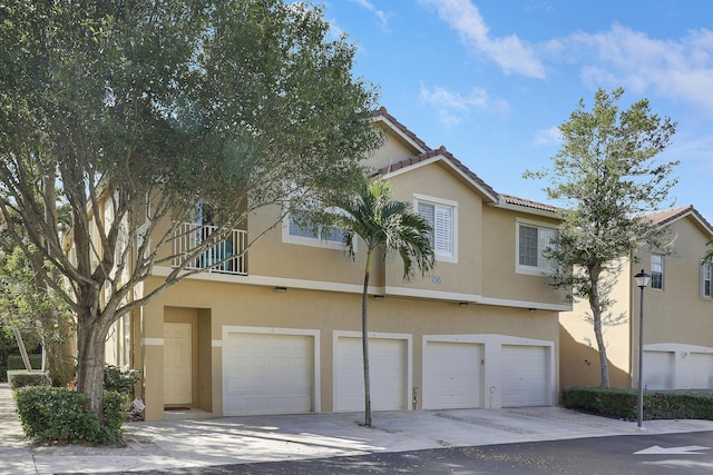 view of front of home with a garage, a tiled roof, driveway, and stucco siding