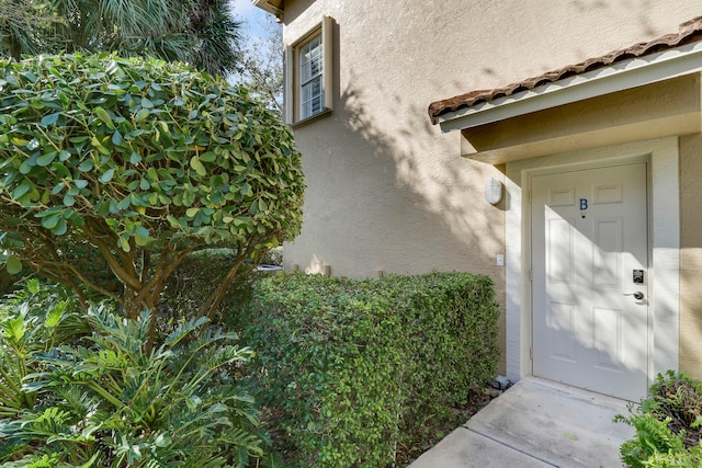 view of exterior entry with a tiled roof and stucco siding