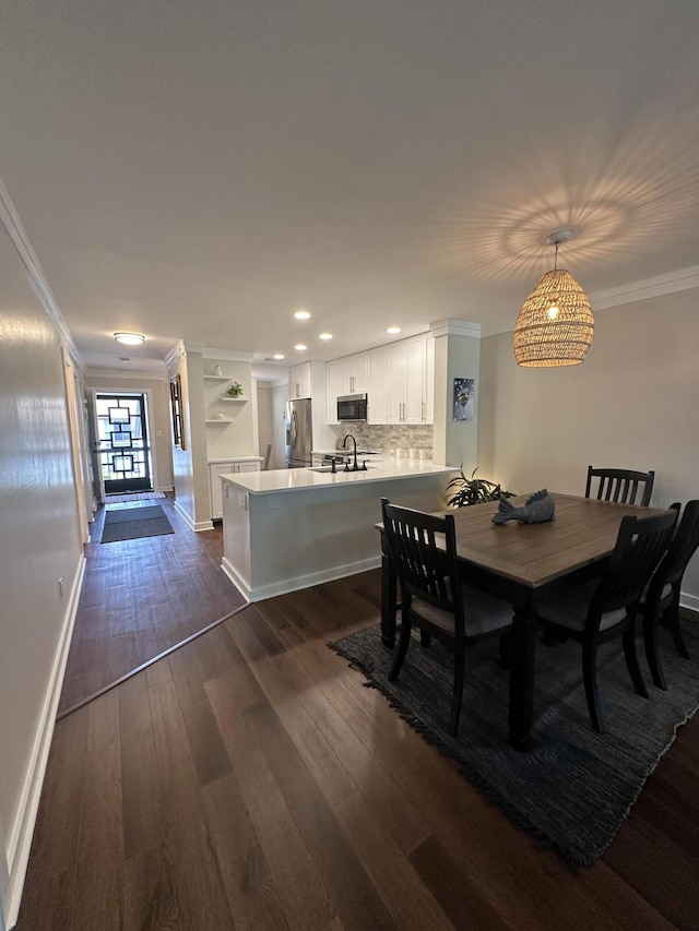 dining space featuring sink, dark hardwood / wood-style flooring, and ornamental molding