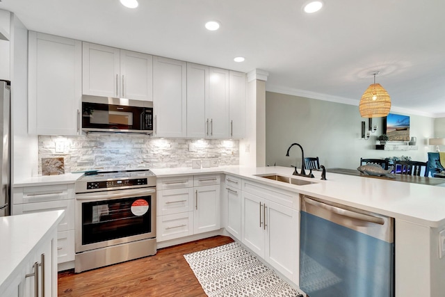 5770 Princess Palm Ct Unit F, Delray Beach, FL 33484 - kitchen featuring appliances with stainless steel finishes, crown molding, a peninsula, light countertops, and decorative backsplash