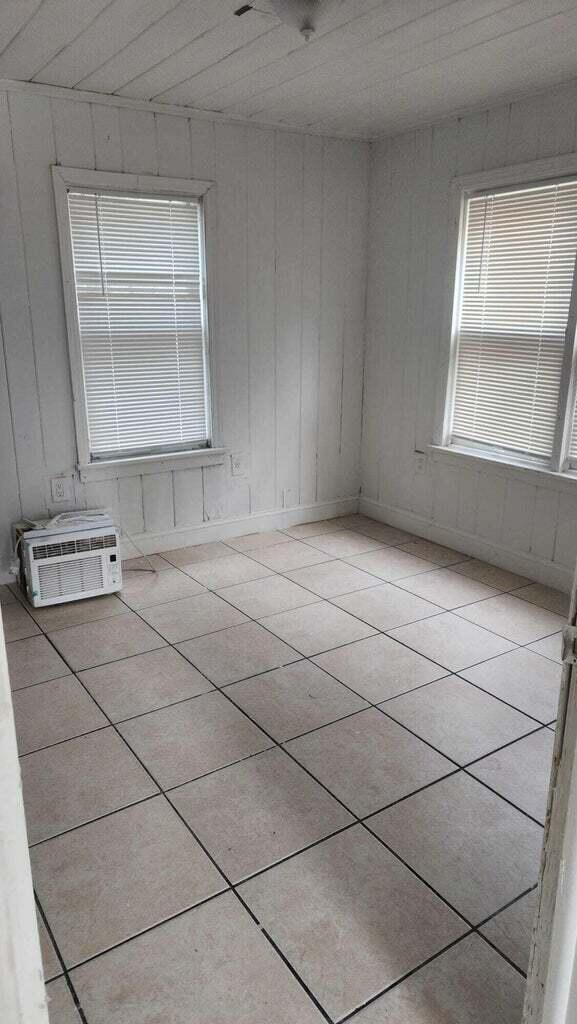 tiled spare room with wood walls, wood ceiling, and a wall mounted air conditioner