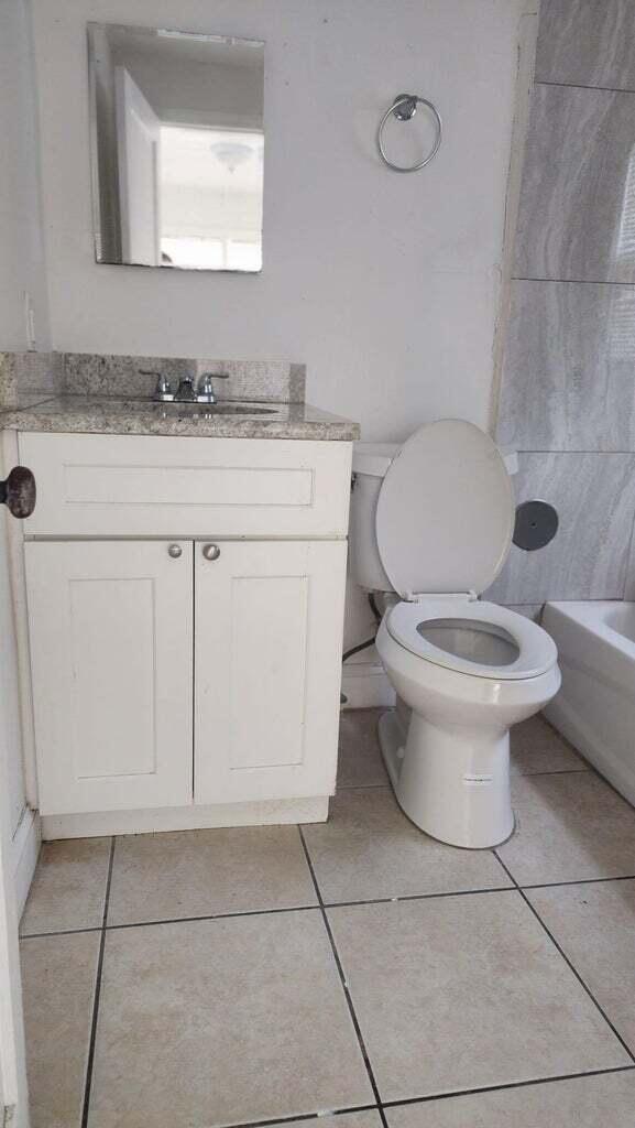 bathroom with toilet, vanity, and tile patterned floors