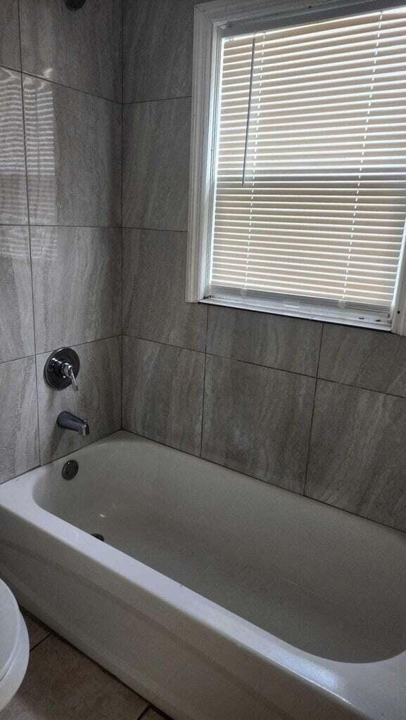 bathroom featuring shower / tub combination and toilet