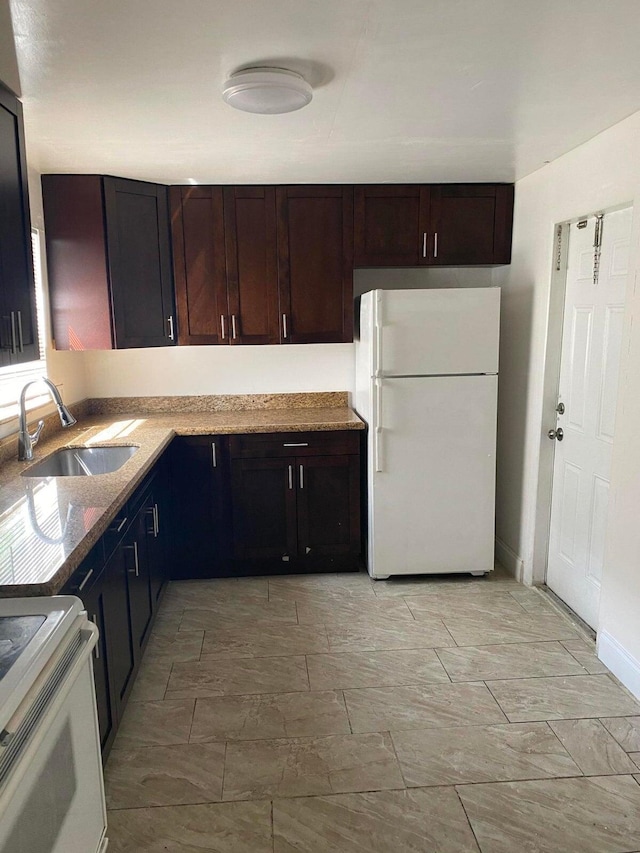 kitchen featuring sink, light stone countertops, dark brown cabinets, stove, and white refrigerator