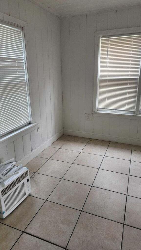 spare room featuring wooden walls and light tile patterned floors