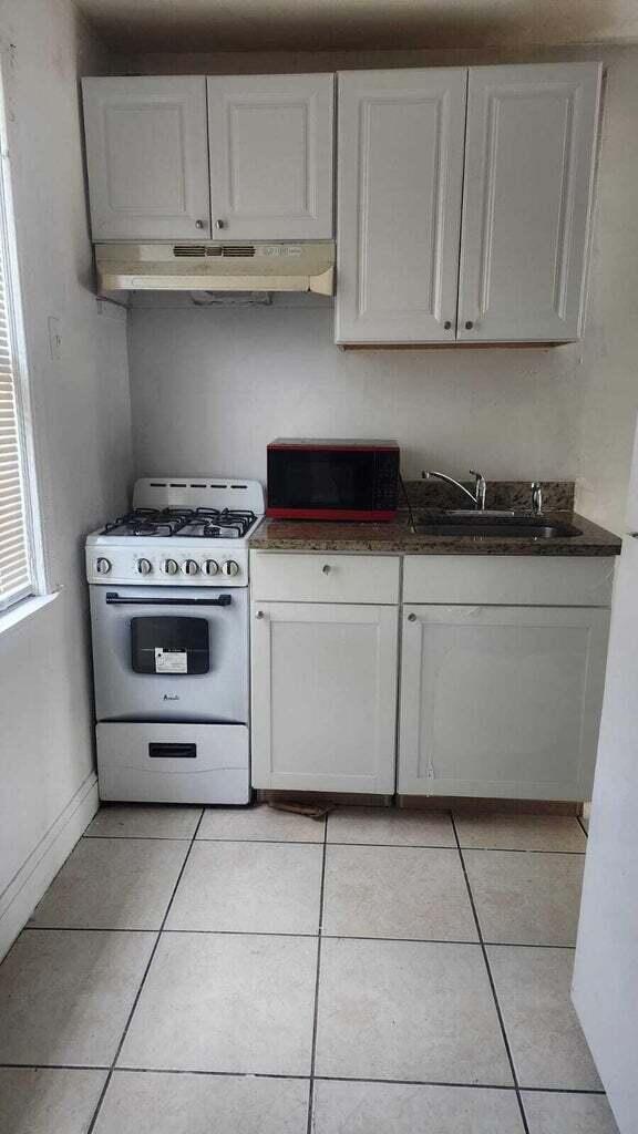 kitchen with gas range gas stove, white cabinetry, and sink