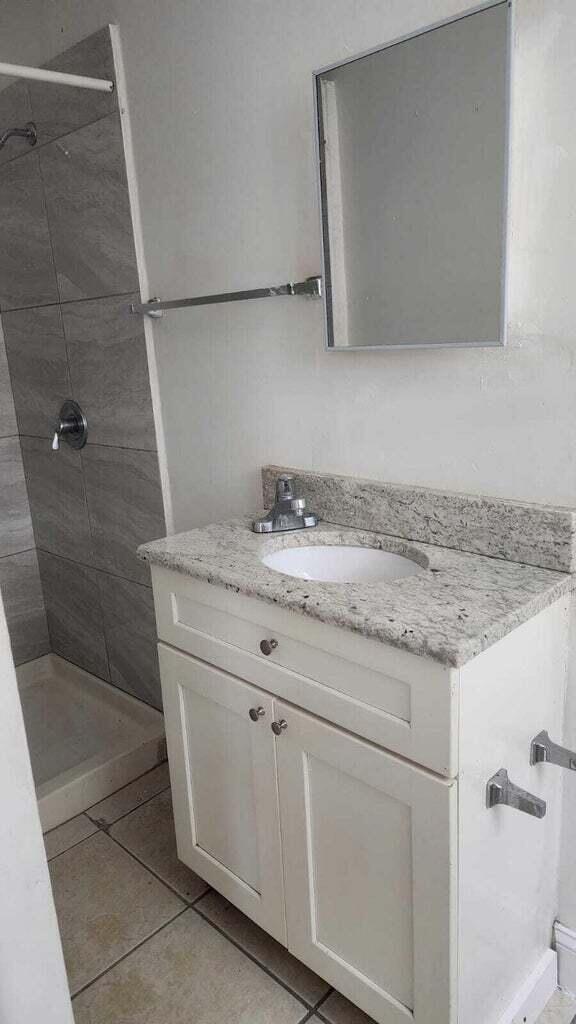 bathroom featuring vanity, tile patterned floors, and a tile shower