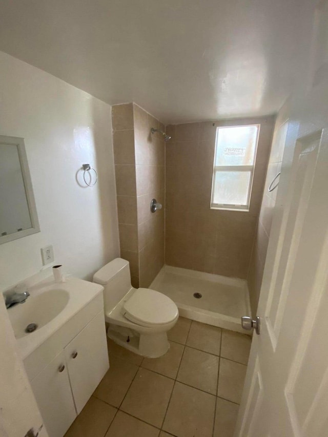 bathroom featuring toilet, vanity, tile patterned floors, and tiled shower