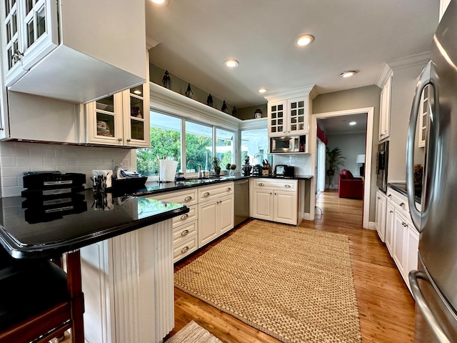 kitchen featuring decorative backsplash, a breakfast bar, stainless steel appliances, and white cabinetry