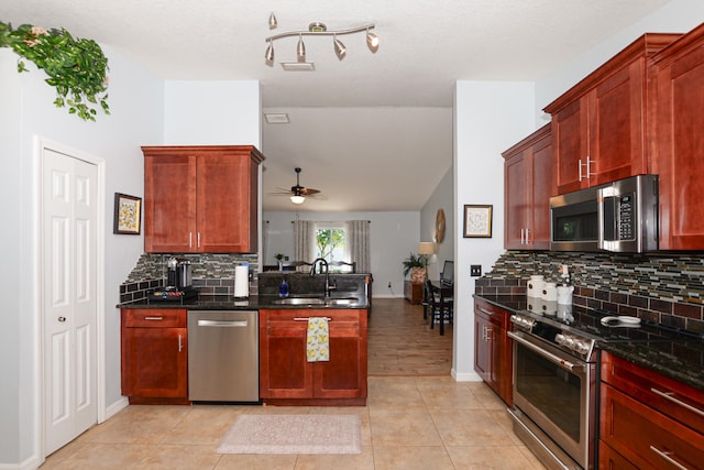 kitchen featuring ceiling fan, sink, stainless steel appliances, dark stone countertops, and decorative backsplash