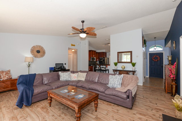 living room featuring ceiling fan, vaulted ceiling, and light wood-type flooring