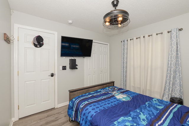 bedroom with hardwood / wood-style floors, a textured ceiling, and a closet