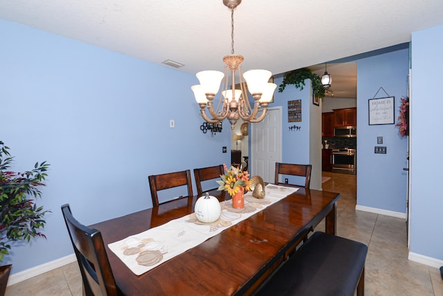 tiled dining space with a textured ceiling and a chandelier