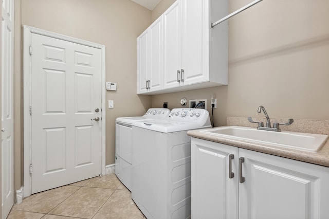 clothes washing area with cabinets, washer and dryer, light tile patterned floors, and sink