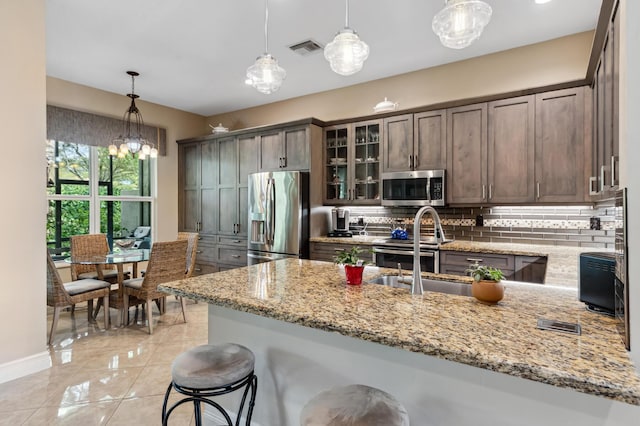8313 Boulder Mountain Ter, Boynton Beach, FL 33473 - kitchen featuring stainless steel appliances, decorative backsplash, light stone countertops, glass insert cabinets, and a peninsula