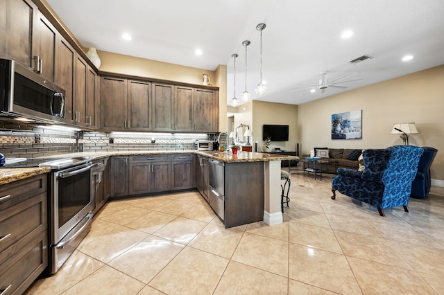 kitchen featuring kitchen peninsula, hanging light fixtures, tasteful backsplash, appliances with stainless steel finishes, and dark stone countertops