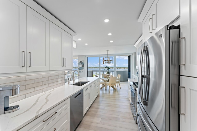 kitchen featuring sink, pendant lighting, decorative backsplash, white cabinets, and appliances with stainless steel finishes