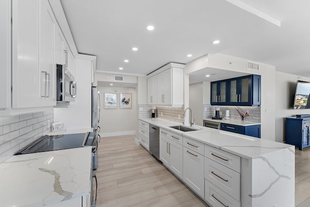 kitchen with white cabinets, light stone counters, light wood-type flooring, and stainless steel appliances