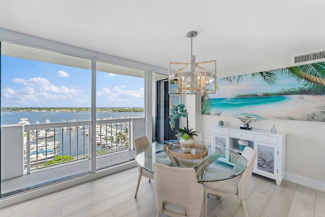 dining space featuring a chandelier, light wood-type flooring, and a water view