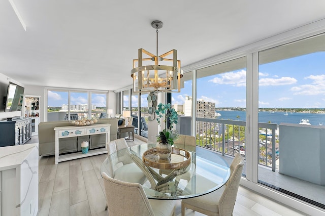 dining area with light hardwood / wood-style floors, a water view, floor to ceiling windows, and a chandelier