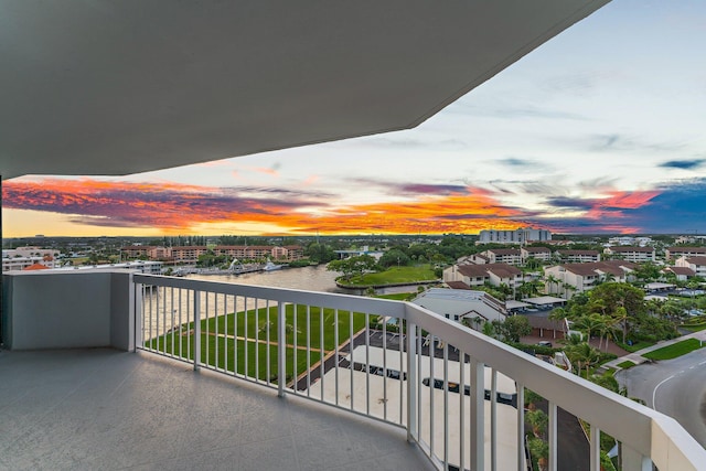 balcony at dusk featuring a water view