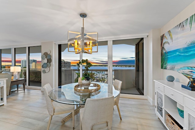 dining space featuring a notable chandelier, expansive windows, and light wood-type flooring