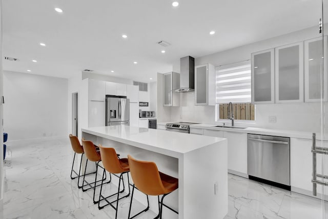 kitchen with white cabinetry, stainless steel appliances, wall chimney range hood, and a kitchen island