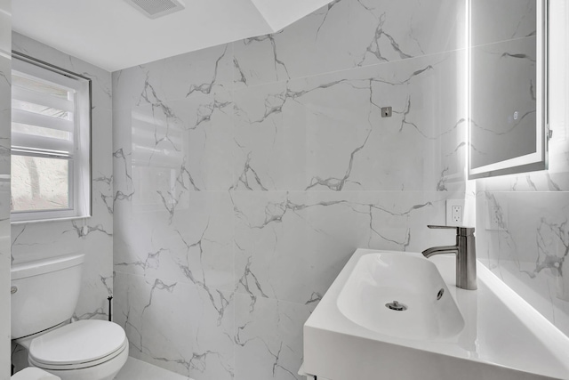 bathroom featuring toilet, tile walls, and sink