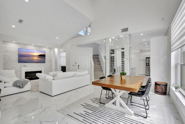 living room featuring high vaulted ceiling and a large fireplace