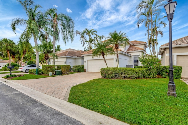 mediterranean / spanish home featuring a front yard and a garage