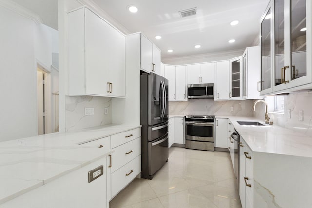 kitchen featuring appliances with stainless steel finishes, tasteful backsplash, light stone counters, sink, and white cabinetry