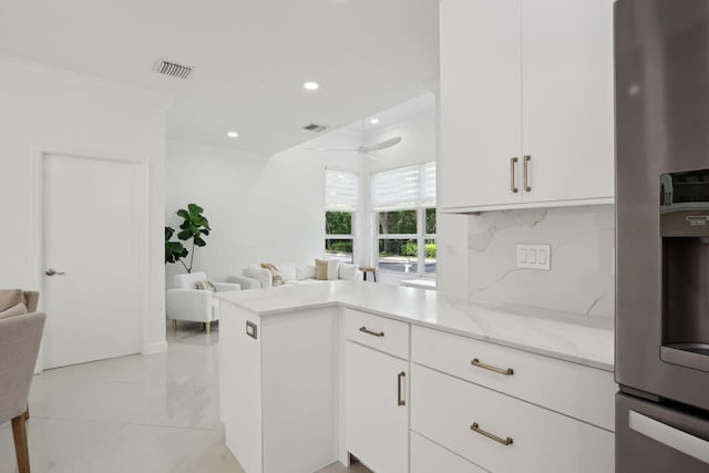 kitchen featuring stainless steel fridge, light stone counters, ceiling fan, crown molding, and white cabinetry