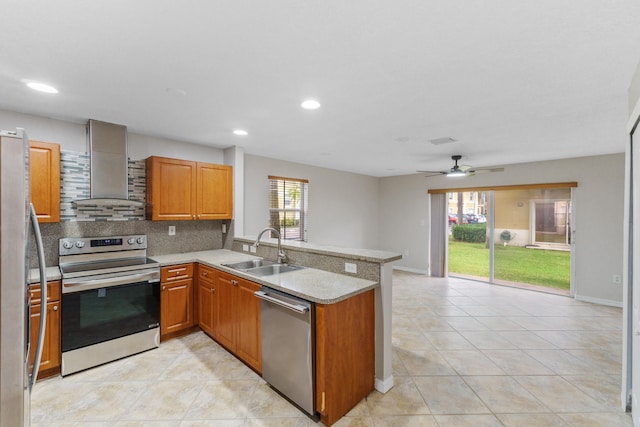 kitchen with sink, stainless steel appliances, wall chimney range hood, tasteful backsplash, and kitchen peninsula