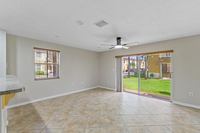 unfurnished room with light tile patterned floors, a textured ceiling, plenty of natural light, and ceiling fan