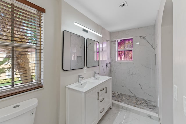 bathroom with tiled shower, vanity, and toilet