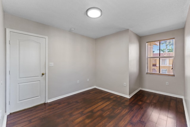 empty room featuring a textured ceiling and dark wood-type flooring