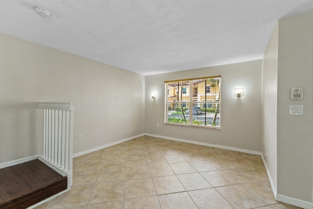 empty room featuring light tile patterned floors and a textured ceiling